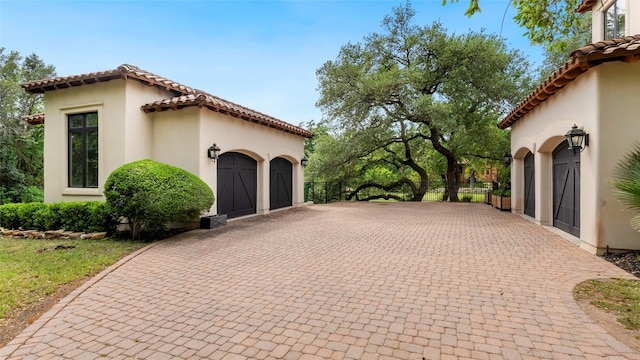 201 Costa Bella Dr, Austin, TX 78734 - view of side of home with decorative driveway, stucco siding, a garage, and a tiled roof