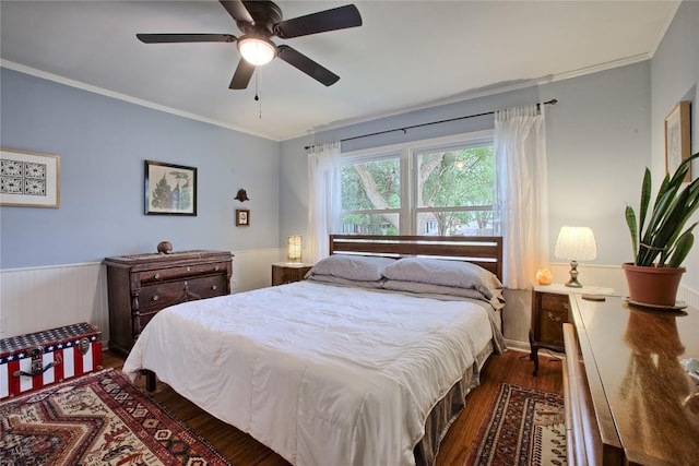 bedroom with crown molding, a ceiling fan, wood finished floors, and a wainscoted wall