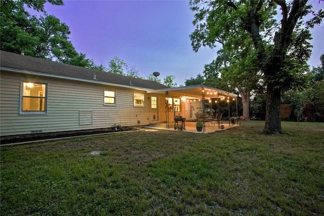 back of house at dusk featuring a yard and a patio