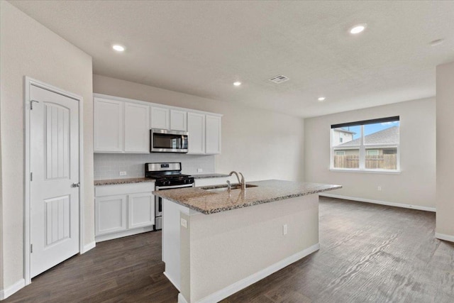 kitchen with white cabinets, light stone countertops, appliances with stainless steel finishes, a sink, and visible vents
