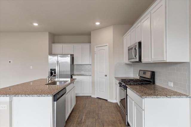 kitchen featuring stainless steel appliances, light stone countertops, white cabinetry, and a sink