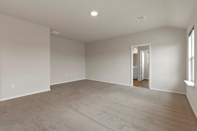 unfurnished room featuring carpet floors, baseboards, vaulted ceiling, and visible vents