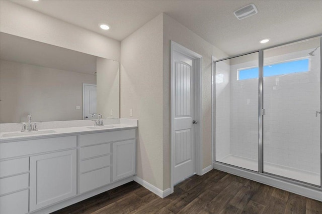 full bathroom featuring a sink, double vanity, a shower stall, and wood finished floors
