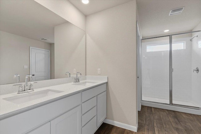 full bath with visible vents, a sink, wood finished floors, and a shower stall