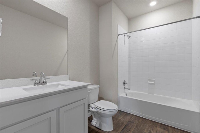 bathroom featuring wood finished floors, vanity, toilet, bathing tub / shower combination, and a textured wall