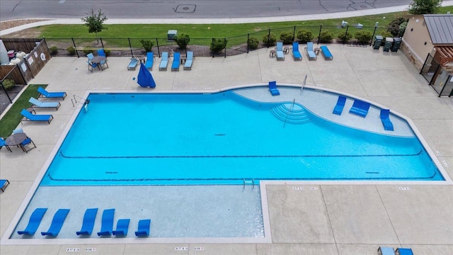 community pool with a patio and fence