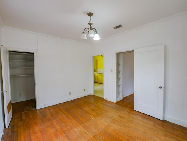 810 E 45th St, Austin, TX 78751 - unfurnished bedroom featuring crown molding, a chandelier, light wood-type flooring, and a walk in closet