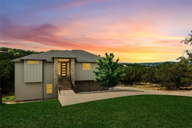 view of front of house featuring fence, a shingled roof, stone siding, and a front yard