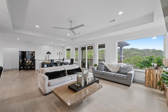 living area with visible vents, recessed lighting, a raised ceiling, a ceiling fan, and light wood finished floors