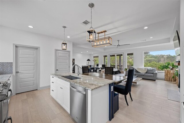 kitchen featuring visible vents, a sink, white cabinets, open floor plan, and stainless steel appliances