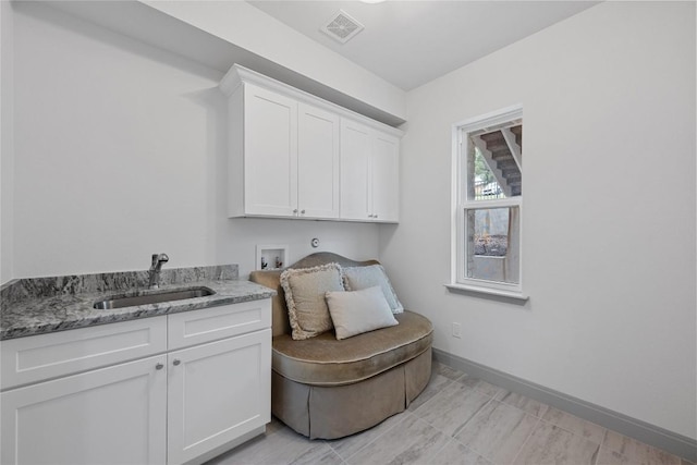 laundry room featuring washer hookup, visible vents, cabinet space, a sink, and baseboards