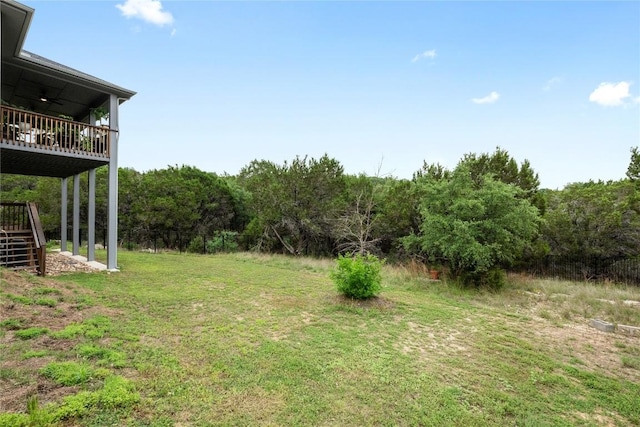 view of yard featuring a wooded view, a wooden deck, and stairway