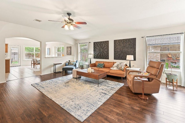 living room with arched walkways, ceiling fan, visible vents, and dark wood-type flooring