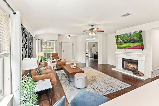 living room with visible vents, wood finished floors, ceiling fan, a lit fireplace, and vaulted ceiling