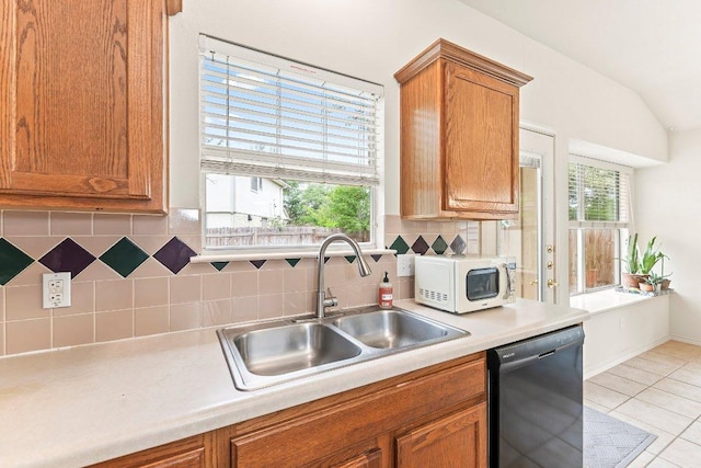 kitchen featuring a sink, white microwave, brown cabinets, and dishwasher