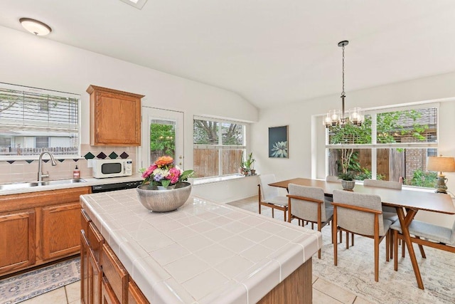 kitchen featuring tile counters, light tile patterned flooring, a sink, and white microwave