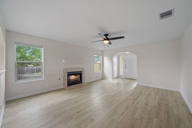 unfurnished living room with visible vents, ceiling fan, plenty of natural light, arched walkways, and light wood finished floors