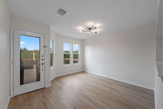 interior space featuring light wood-style floors, baseboards, an inviting chandelier, and visible vents