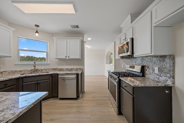 kitchen featuring visible vents, light wood-style floors, white cabinetry, a sink, and stainless steel appliances