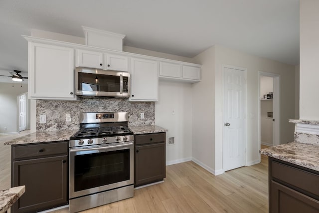 kitchen with white cabinets, ceiling fan, appliances with stainless steel finishes, light wood-style floors, and decorative backsplash