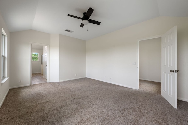unfurnished room featuring visible vents, lofted ceiling, baseboards, ceiling fan, and carpet flooring