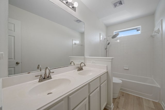 full bath with toilet, visible vents, a sink, and wood finished floors