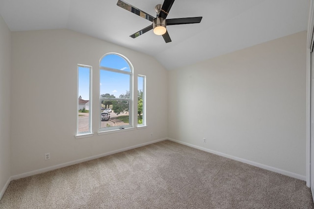 carpeted spare room with baseboards, ceiling fan, vaulted ceiling, and a healthy amount of sunlight