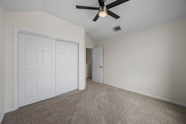 unfurnished bedroom with carpet floors, baseboards, lofted ceiling, visible vents, and a closet