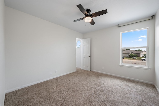 carpeted empty room featuring baseboards and ceiling fan