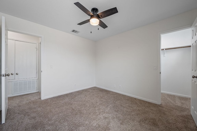 unfurnished bedroom featuring baseboards, carpet, a spacious closet, and visible vents