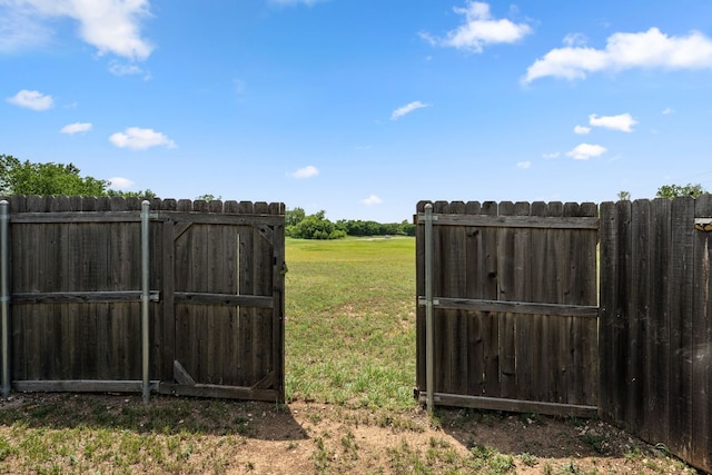 view of gate featuring fence and a lawn