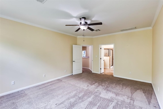 carpeted empty room featuring visible vents, ornamental molding, baseboards, and ceiling fan
