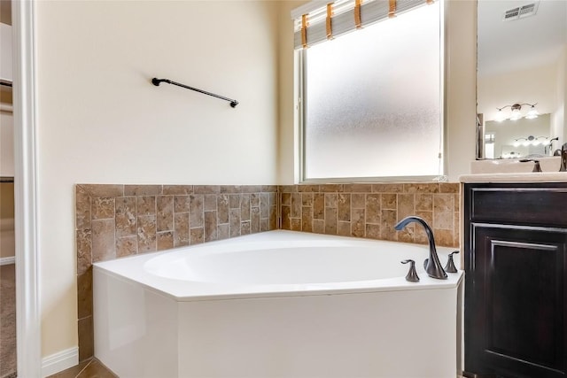 bathroom featuring visible vents, a garden tub, and vanity