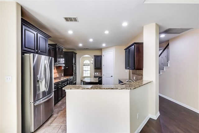 kitchen with visible vents, arched walkways, decorative backsplash, and stainless steel appliances