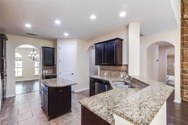kitchen featuring visible vents, a sink, a peninsula, arched walkways, and dishwasher