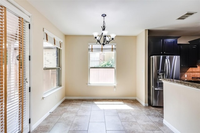 unfurnished dining area with light tile patterned flooring, a notable chandelier, visible vents, and baseboards