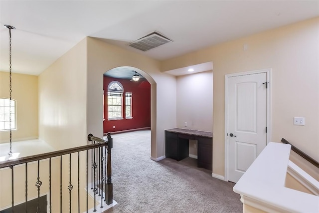 hall featuring arched walkways, baseboards, visible vents, and carpet