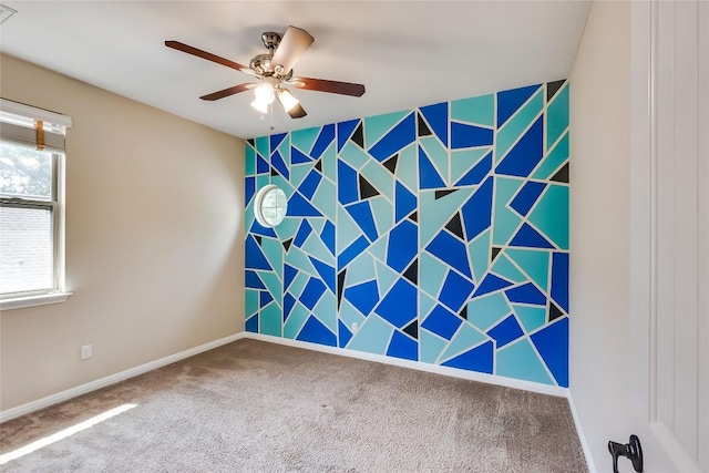 carpeted empty room featuring baseboards, a ceiling fan, and an accent wall