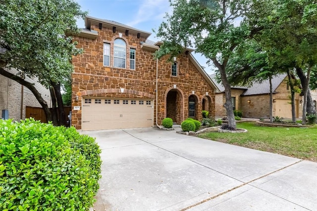 view of front facade with an attached garage, driveway, and stone siding