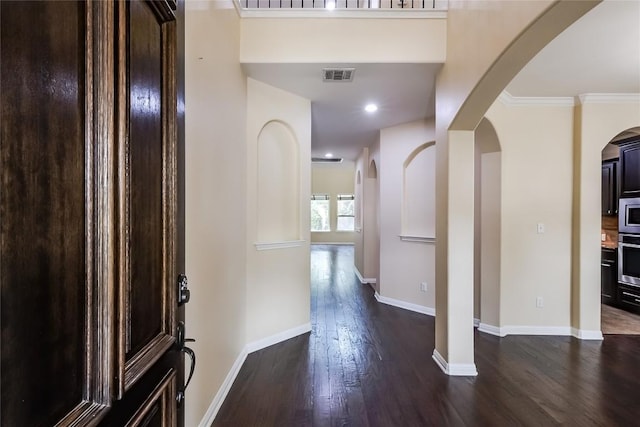 foyer featuring visible vents, crown molding, baseboards, dark wood-style floors, and arched walkways