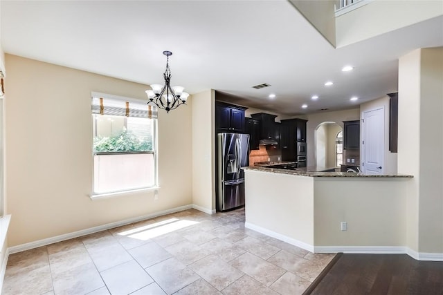 kitchen with arched walkways, stainless steel fridge with ice dispenser, dark stone countertops, a peninsula, and an inviting chandelier