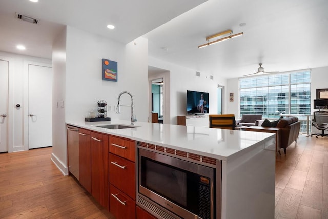 kitchen with modern cabinets, a sink, open floor plan, light wood-style floors, and stainless steel appliances