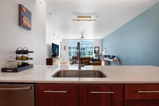 kitchen with ceiling fan, a sink, light countertops, open floor plan, and stainless steel dishwasher