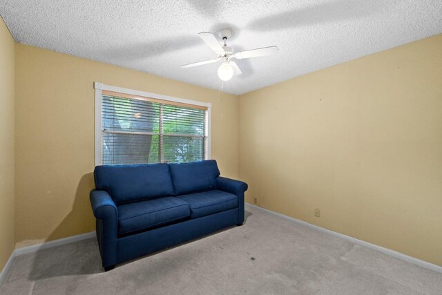 sitting room with carpet floors, ceiling fan, baseboards, and a textured ceiling