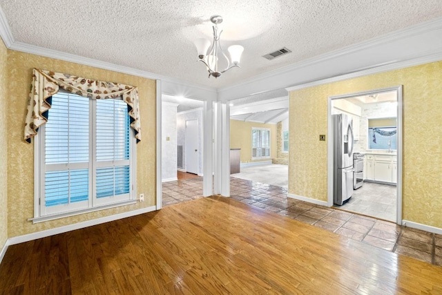 interior space with crown molding, a notable chandelier, baseboards, wood finished floors, and visible vents