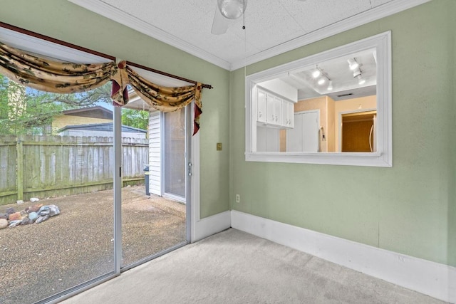 interior space with a ceiling fan, rail lighting, carpet floors, baseboards, and ornamental molding