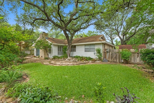 rear view of property with a lawn, fence, a chimney, and a gate