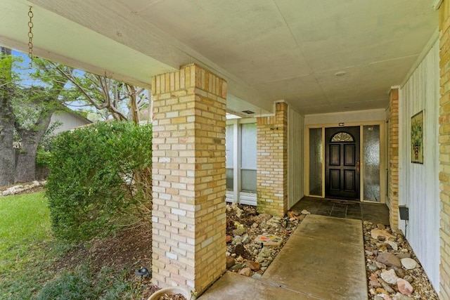 entrance to property with a porch and brick siding