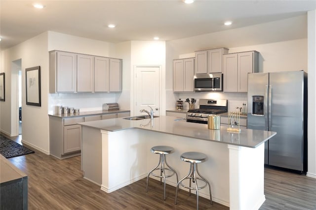 kitchen featuring stainless steel appliances, gray cabinets, dark wood-style floors, and a sink