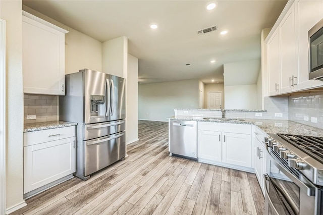 10401 American Paint Way, Manor, TX 78653 - kitchen with appliances with stainless steel finishes, a sink, light wood-type flooring, white cabinetry, and a peninsula